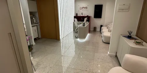 Corredor de entrada e circulação da clínica Eva com iluminação linear e recepção ao fundo